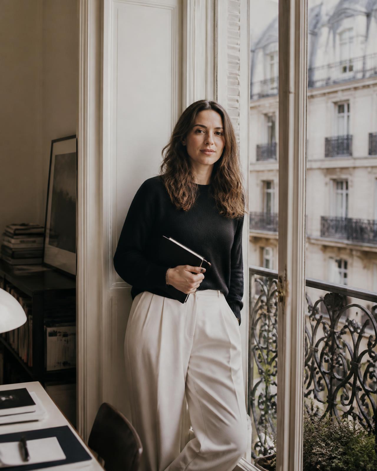 Fondatrice devant une fenêtre parisienne, carnet à la main